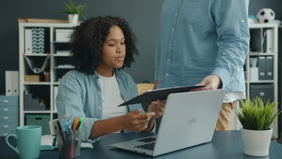 University staff reviewing records at a laptop